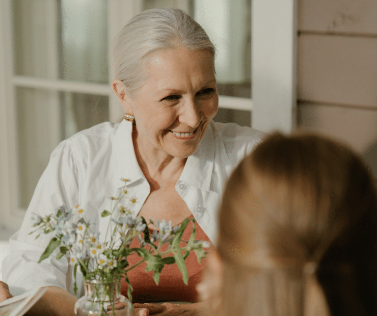 une personne âgée qui tient dans ses mains des fleurs